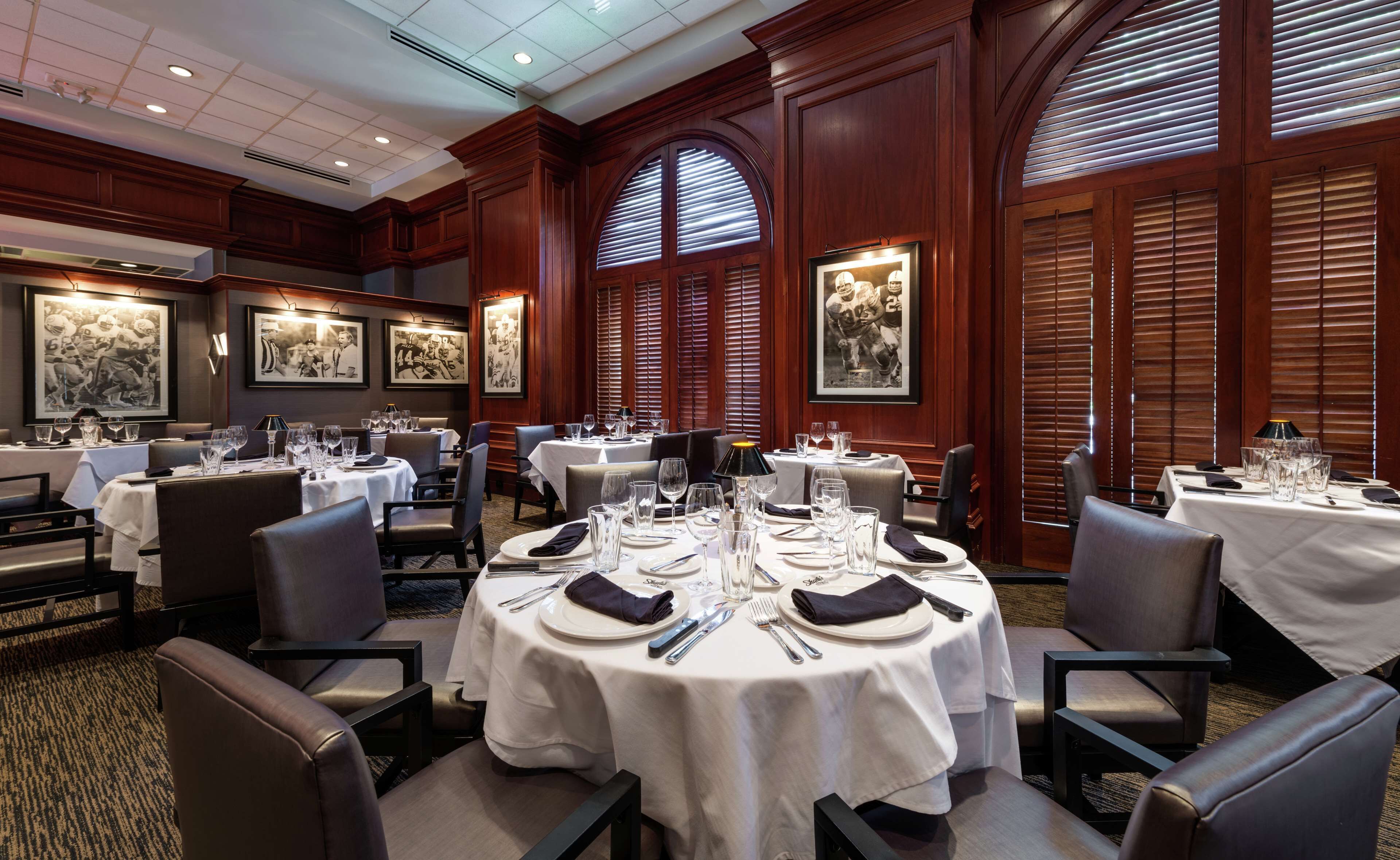 A formal dining area with round tables set for multiple guests, featuring white tablecloths and silverware.