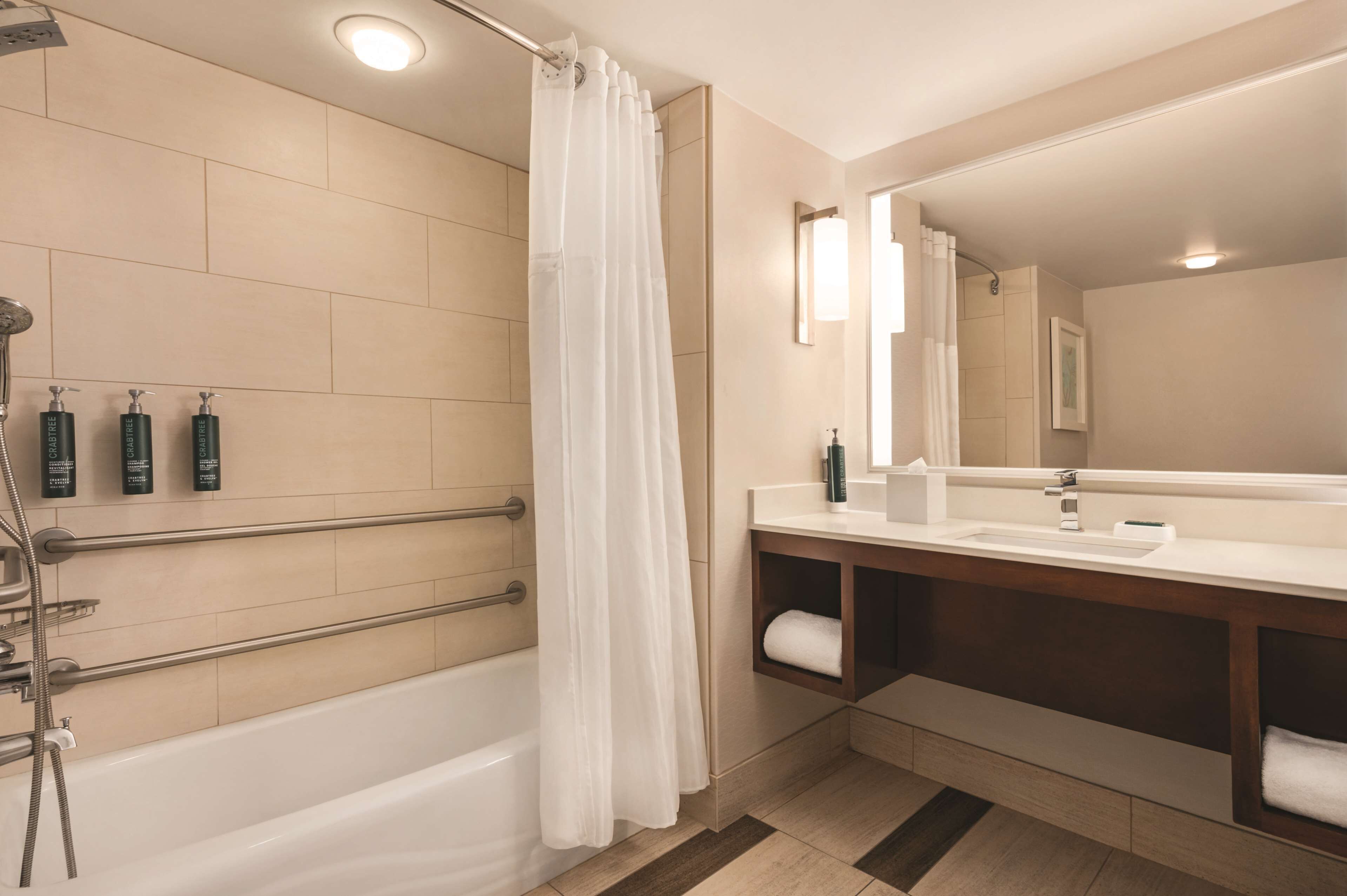 A modern bathroom with a bathtub, shower, and vanity.