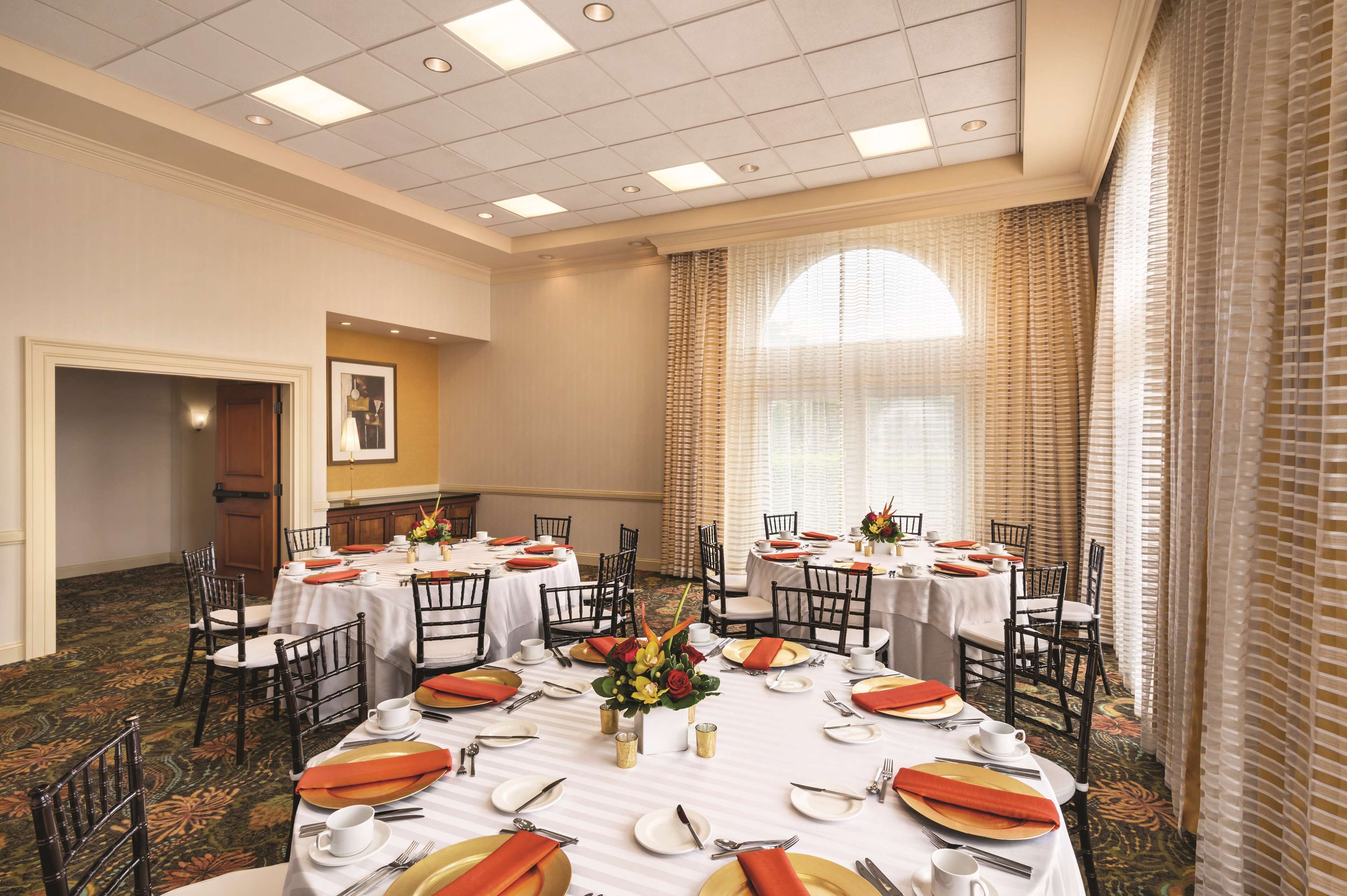 A conference room with round tables, chairs, and a carpeted floor.