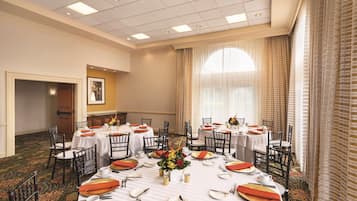 A conference room with round tables, chairs, and a carpeted floor.