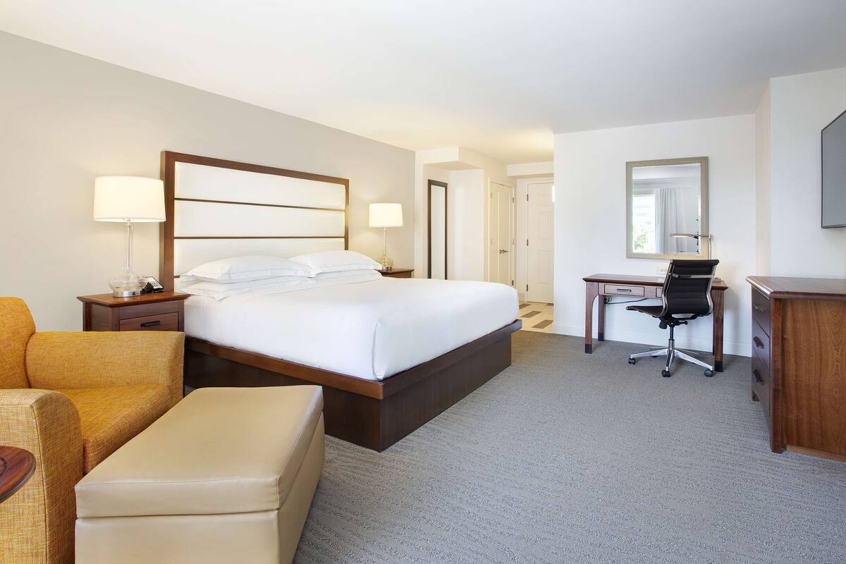 Une chambre d’hôtel avec un grand lit, un bureau, une chaise, un canapé et une petite table.