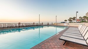 A swimming pool with lounge chairs, a tiled walkway, and a view of the ocean. - Hampton Inn Daytona Shores - Oceanfront (Daytona Beach Shores)