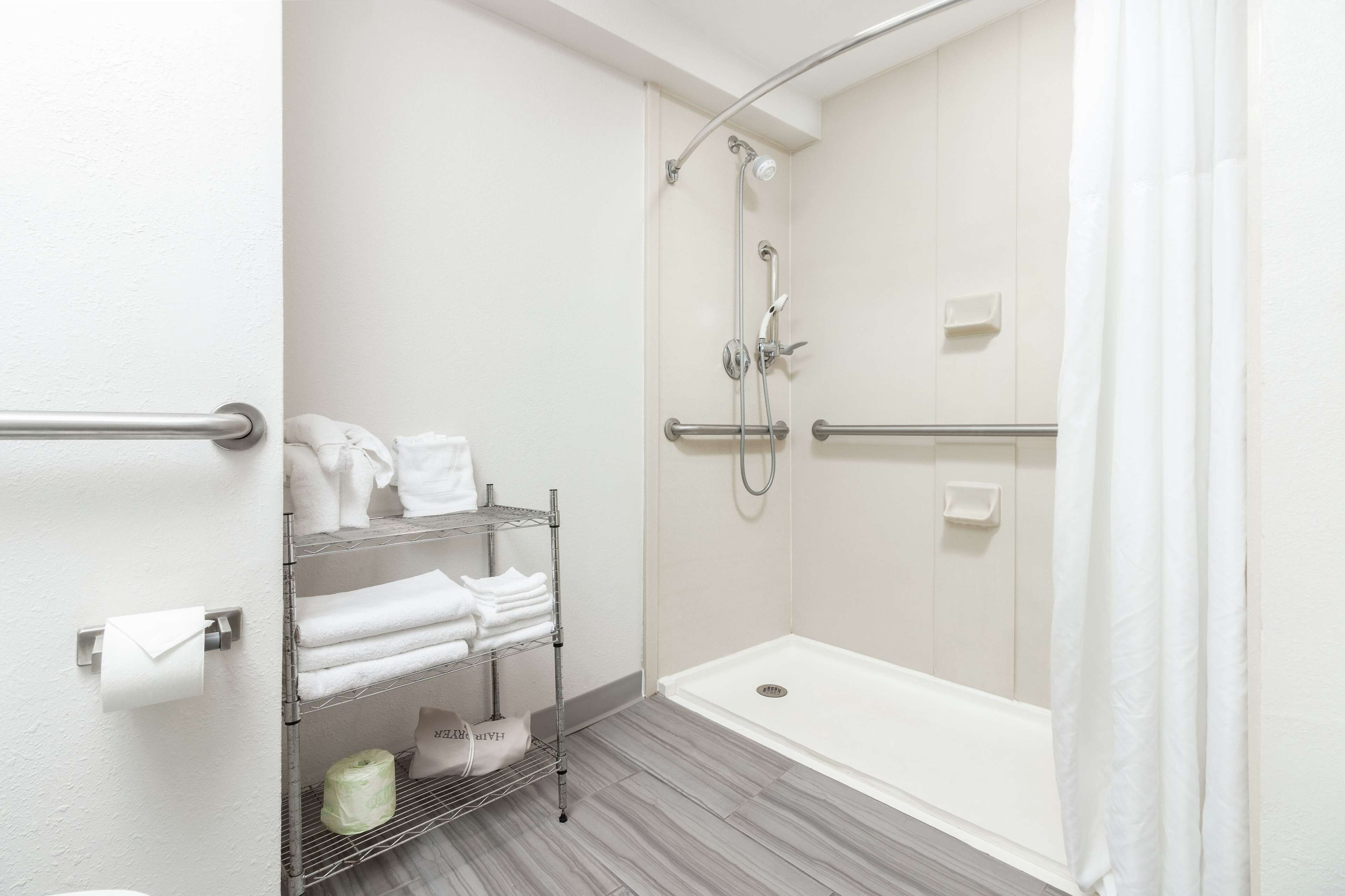 A modern bathroom with a walk-in shower, a bathtub, and a towel rack with neatly folded towels.