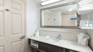 A bathroom with a white sink, a mirror, and a towel rack.