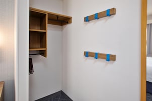 Una habitación con un armario de madera, perchero y dos ganchos en la pared.