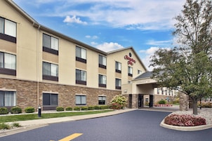 Un hotel Hampton Inn con entrada despejada, fachada de piedra y jardín delantero ajardinado.