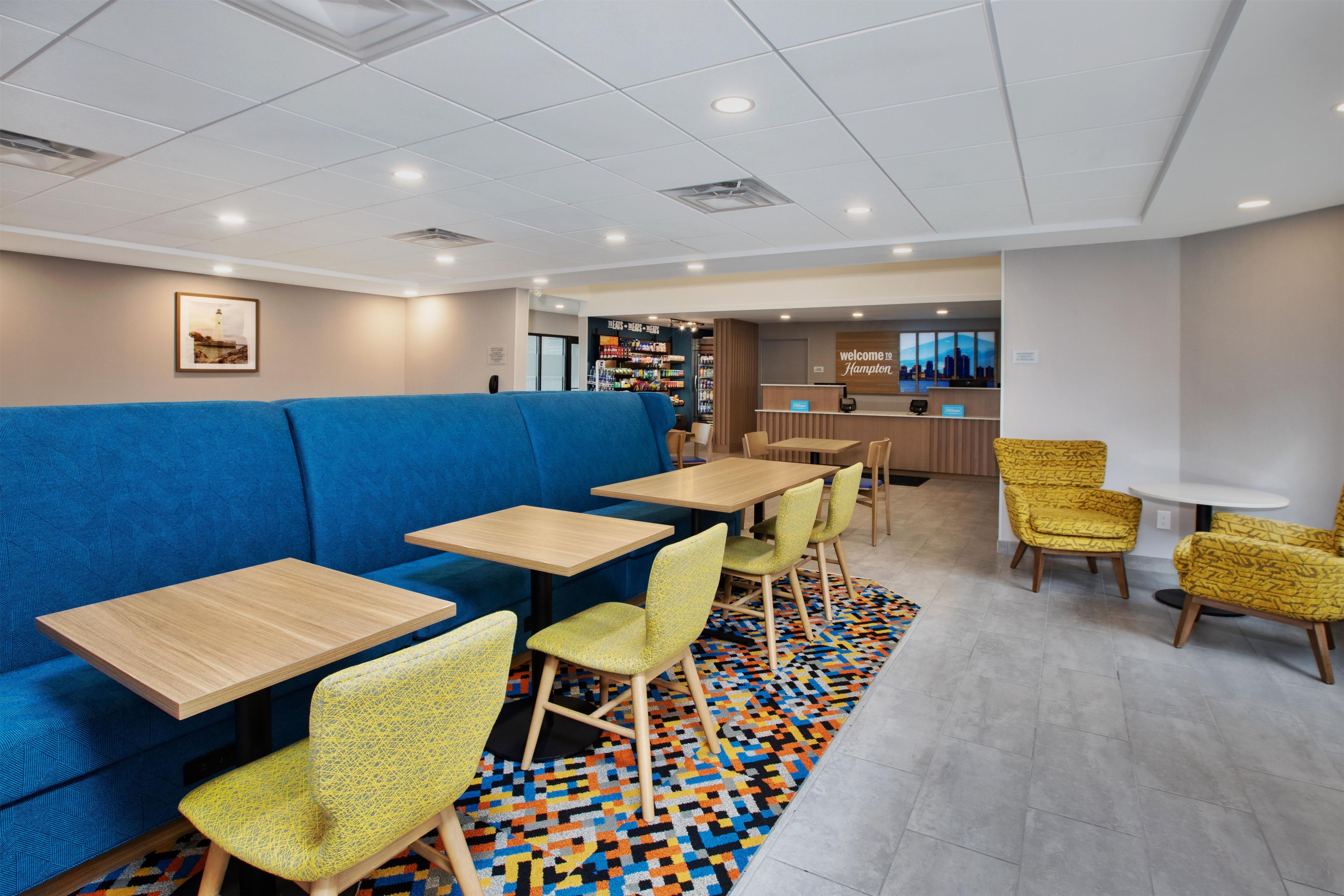 A hotel lobby with a blue sofa, yellow chairs, and a reception desk.