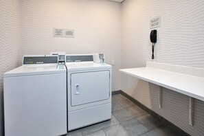 A laundry area with a white wall, a white counter, and a phone mounted on the wall. - Hampton Inn Hotel Detroit/Belleville-Airport Area (Belleville)
