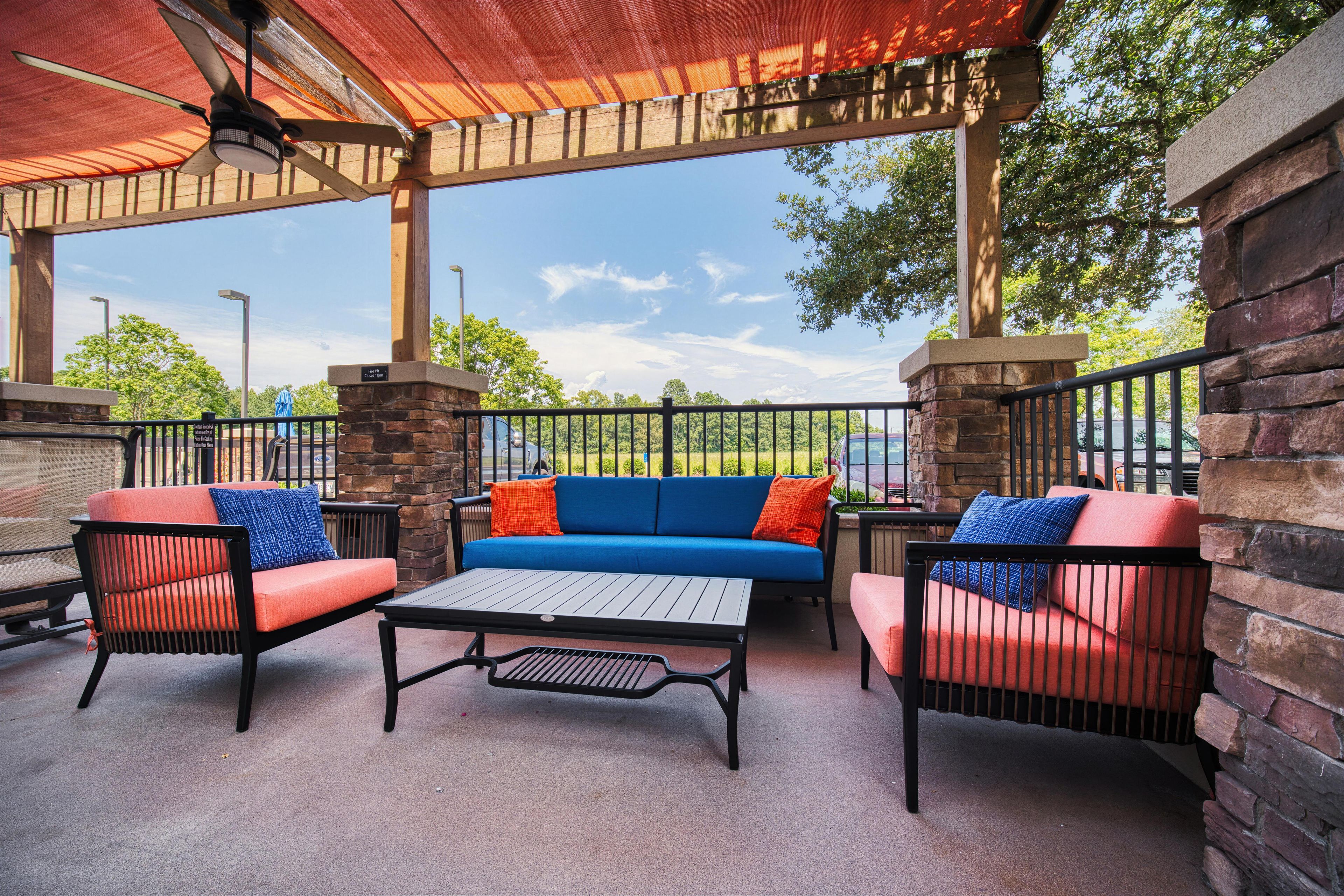 An outdoor patio with a covered seating area, a table, and a view of the street.