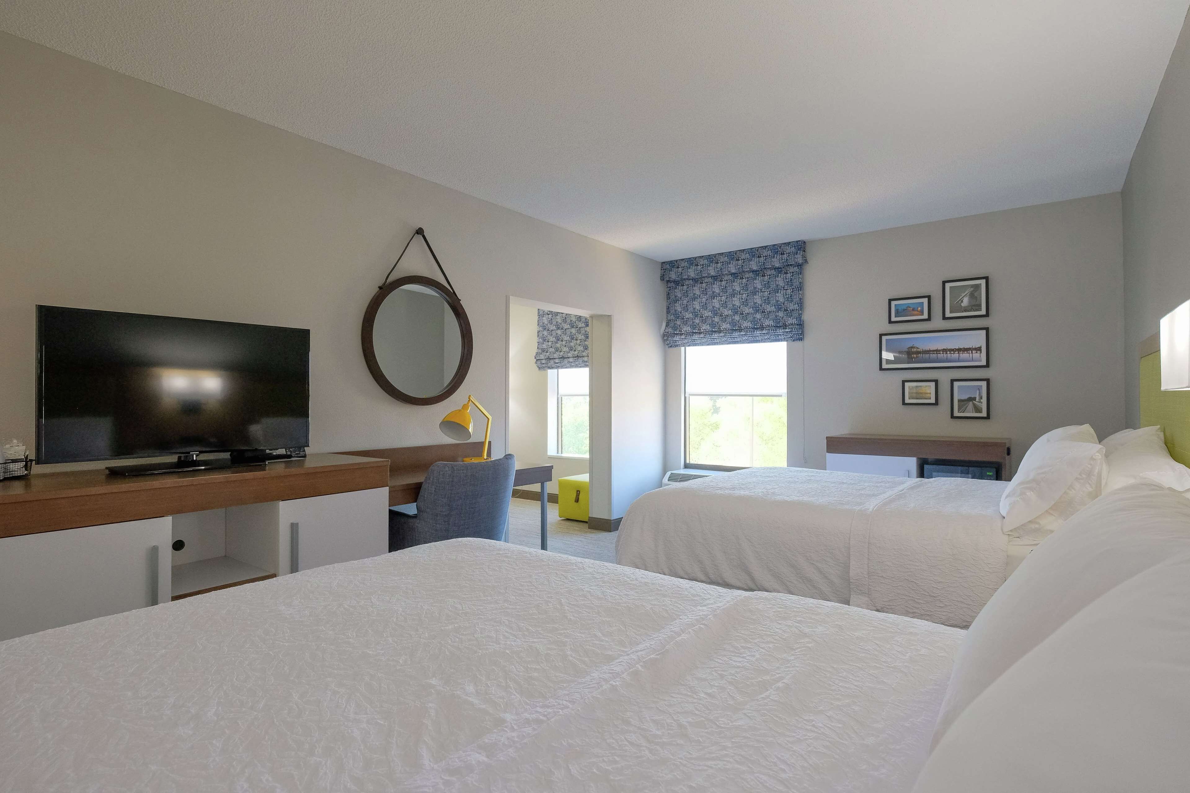 A hotel room with two beds, a TV, a desk, and a chair.