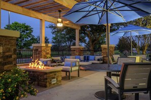 Un patio al aire libre con muros de piedra, una chimenea, asientos y sombrillas.