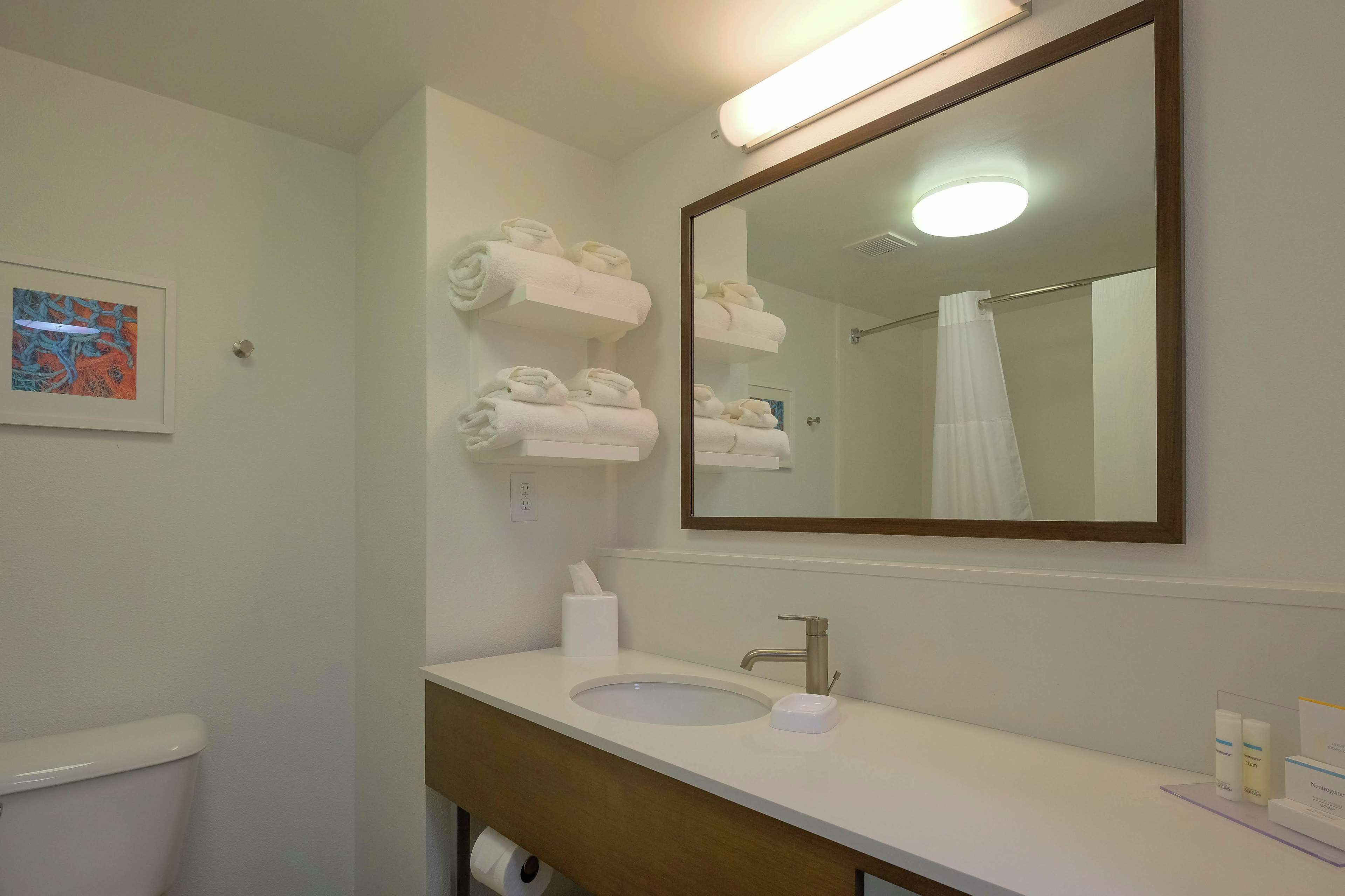 Une salle de bain équipée d’un lavabo, d’un miroir, de porte-serviettes et de toilettes.