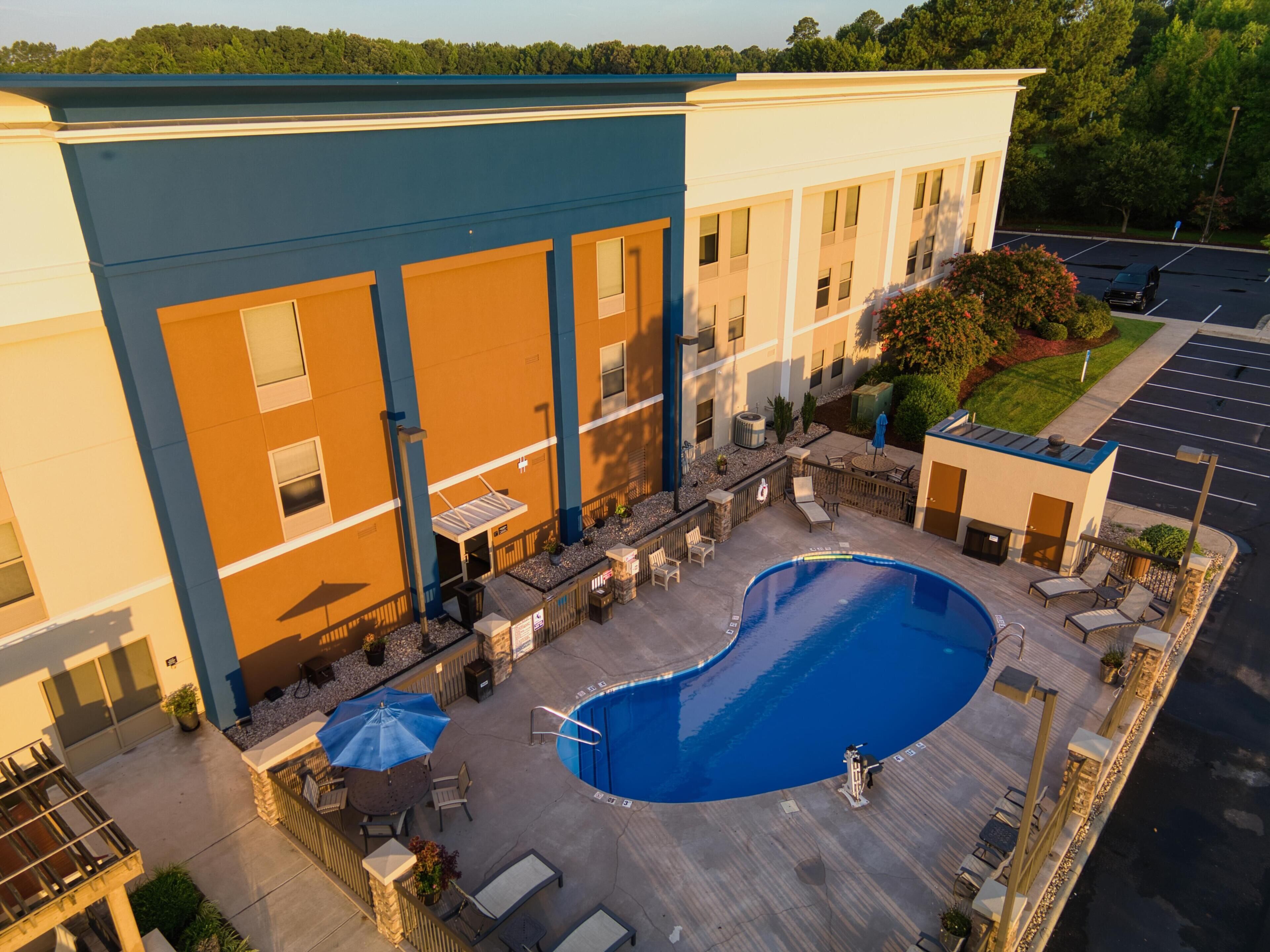Um hotel com piscina, área de estar ao ar livre e estacionamento.