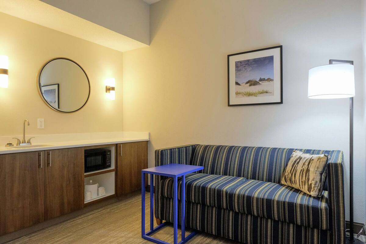 Un baño moderno con lavamanos, espejo y un taburete azul.