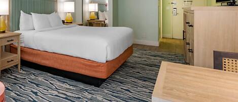 Una habitación de hotel con cama, mesitas de noche, lámparas, cómoda y televisor.