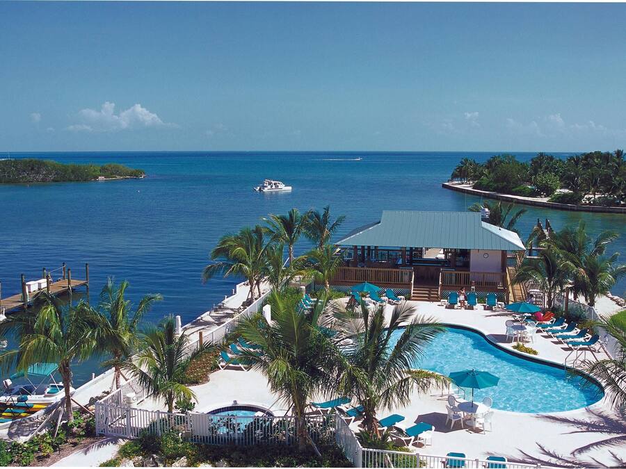 Un resort con piscina, lettini e vista sull'oceano.