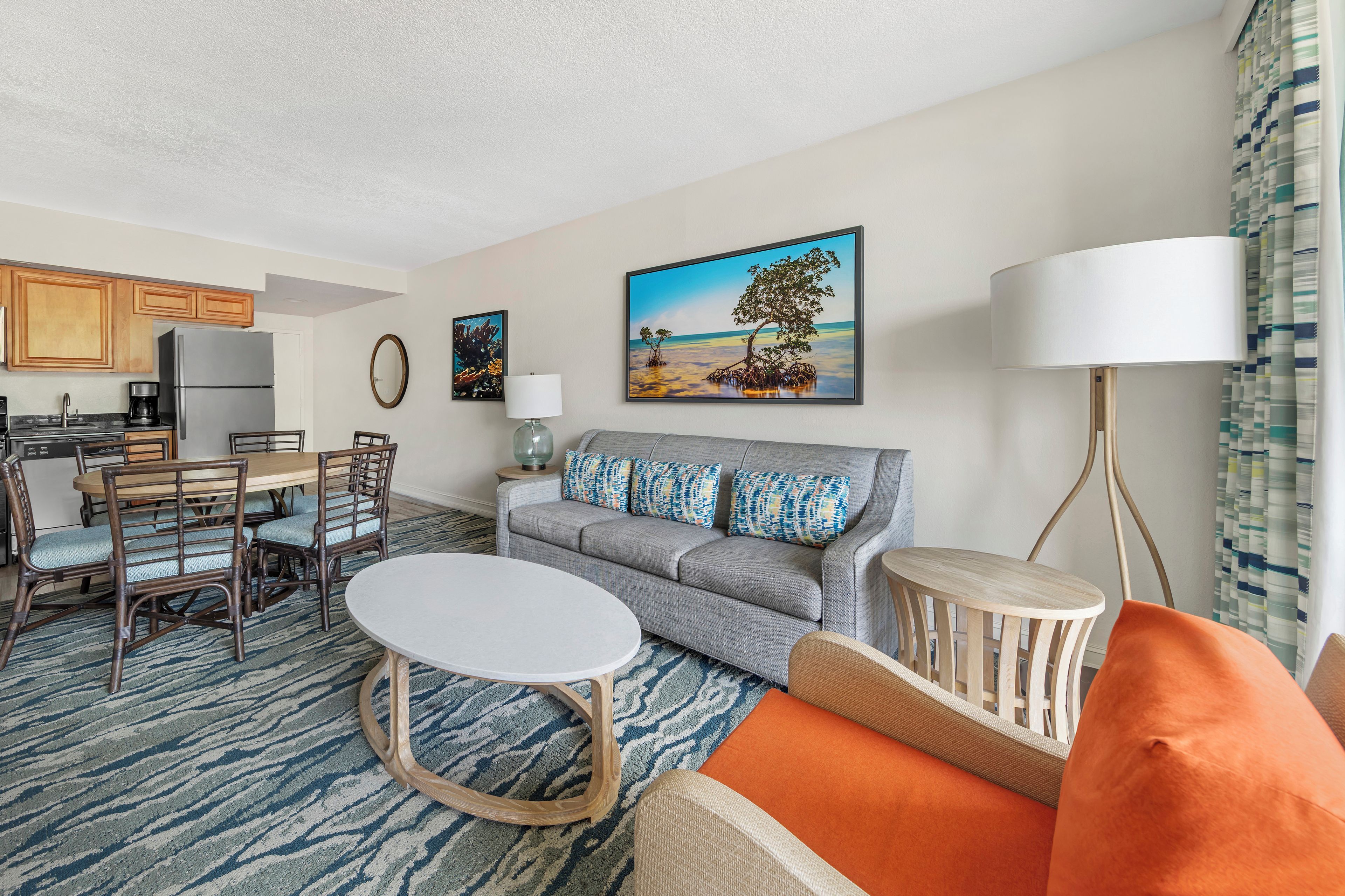 A living room with a sofa, coffee table, and a dining area with chairs and a table.