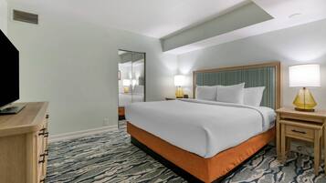 Een hotelkamer met een bed, nachtkastjes, een televisie en een kamerbreed tapijt met een patroon.