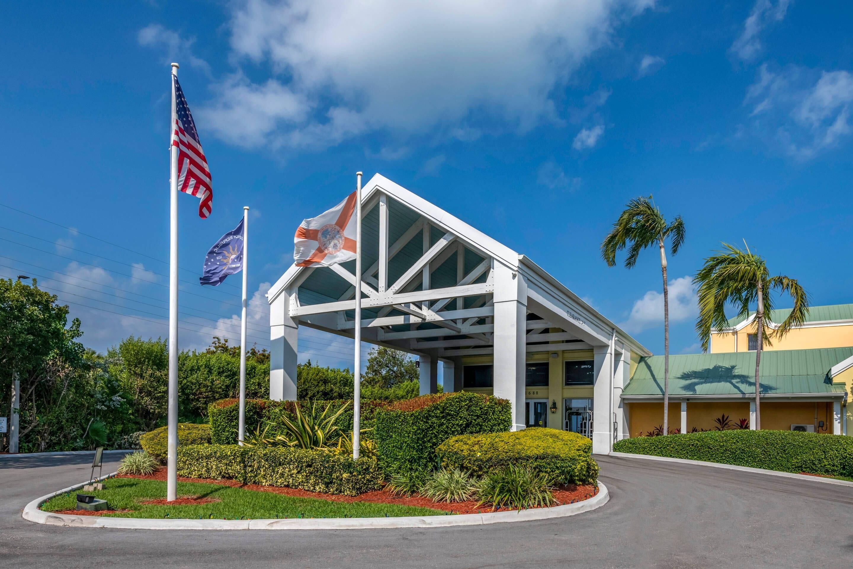 A hotel with a modern architectural design, featuring a prominent entrance with a glass canopy and a flagpole with the American flag.