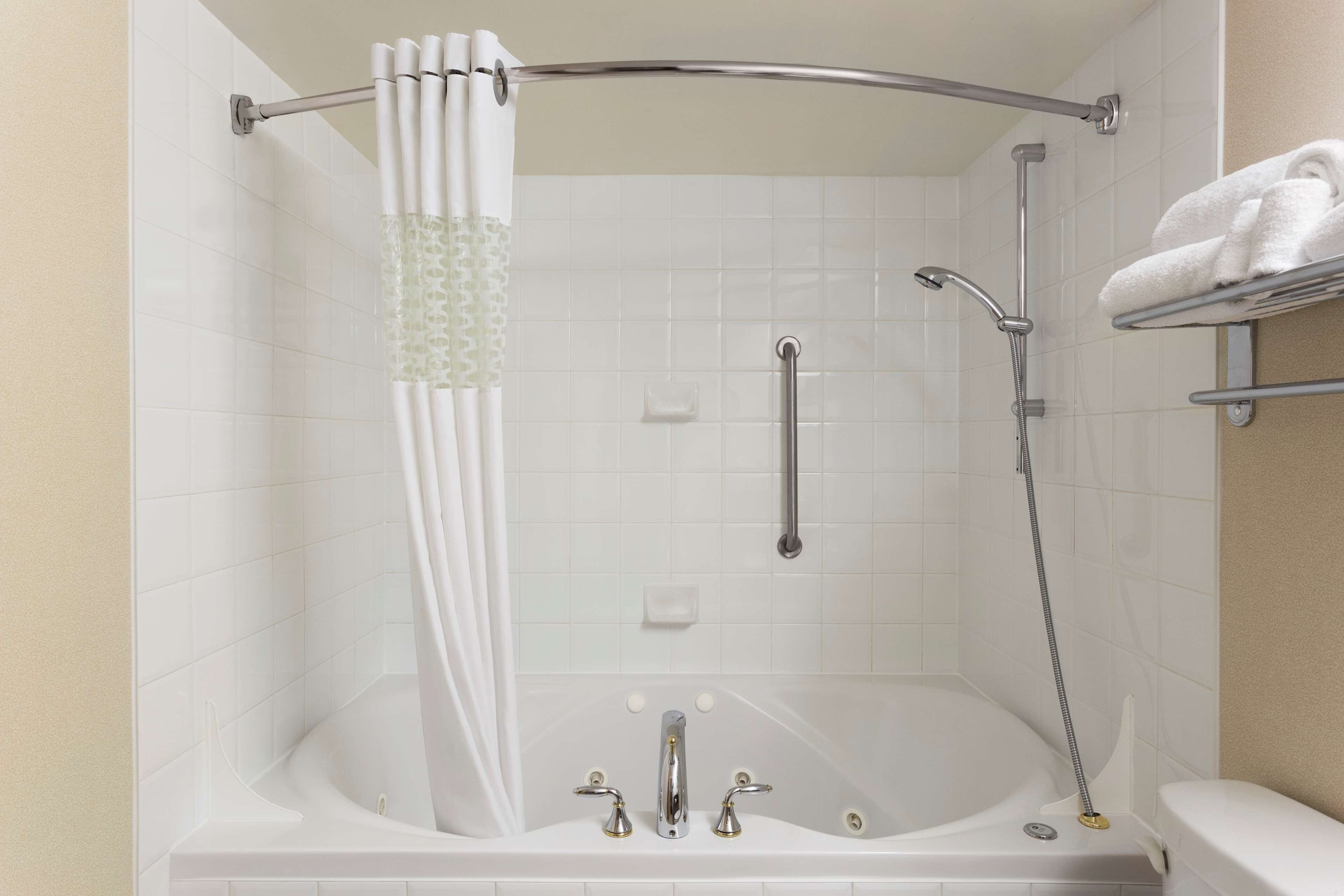 A bathroom with a bathtub, shower, and a towel rack.