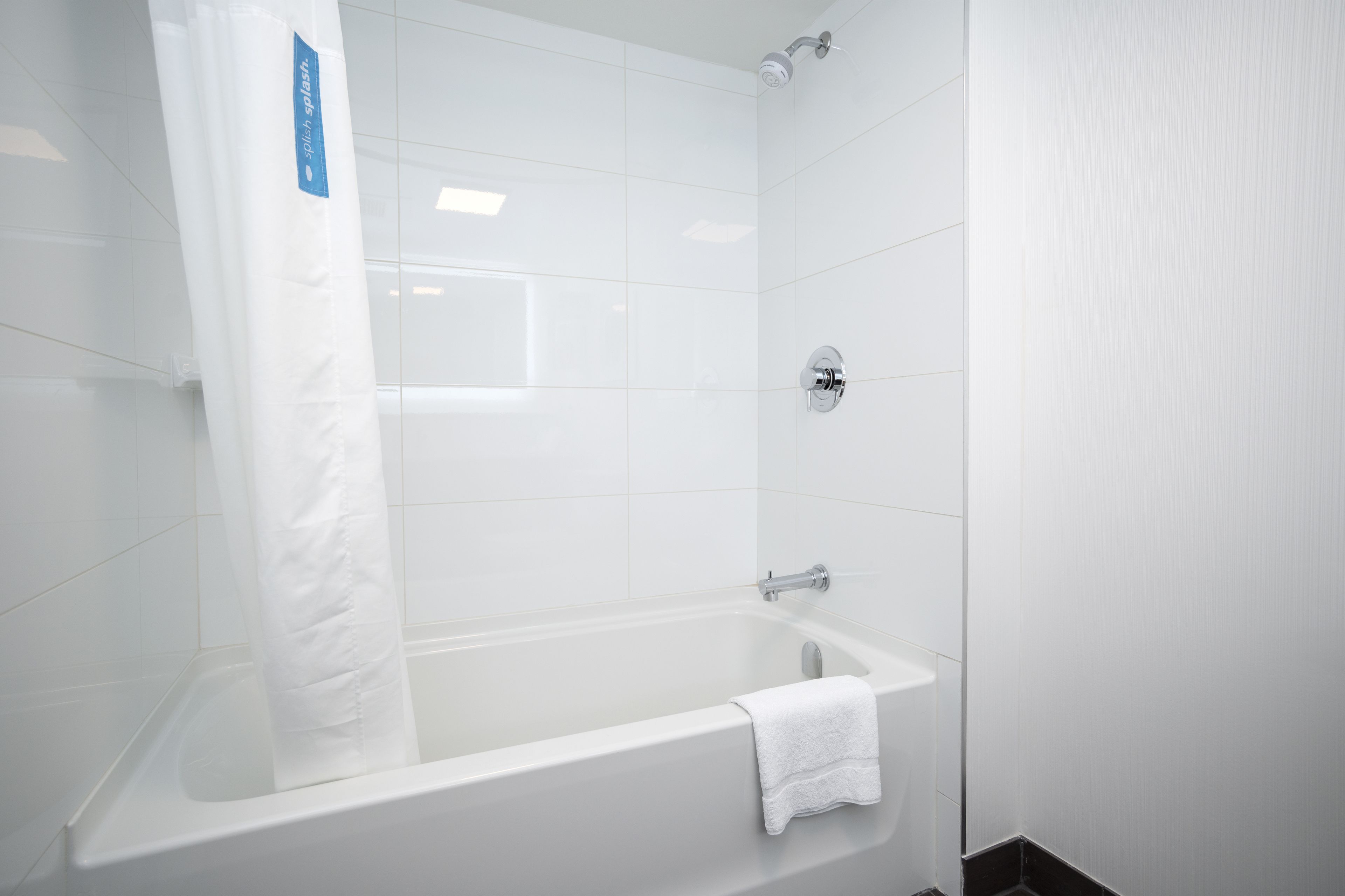 A modern bathroom with a bathtub, shower, and white tiled walls.