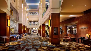 A spacious hotel lobby with a high ceiling, a central staircase, and a patterned carpet. - Hyatt Regency Calgary (Calgary)