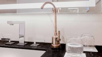 Une salle de bain moderne avec un plan de toilette en marbre noir, un lavabo blanc et un grand miroir.