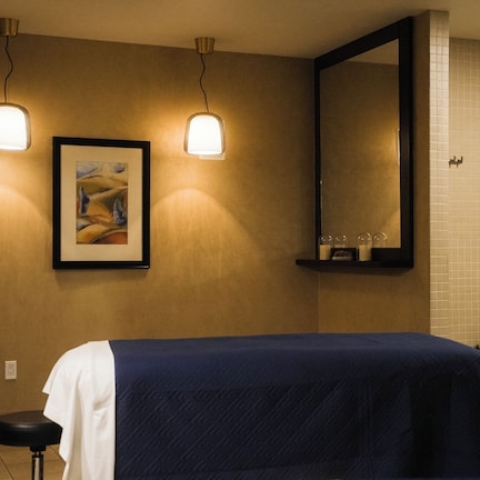 A hotel room with a bed, a wall-mounted picture, a sink, and a mirror.