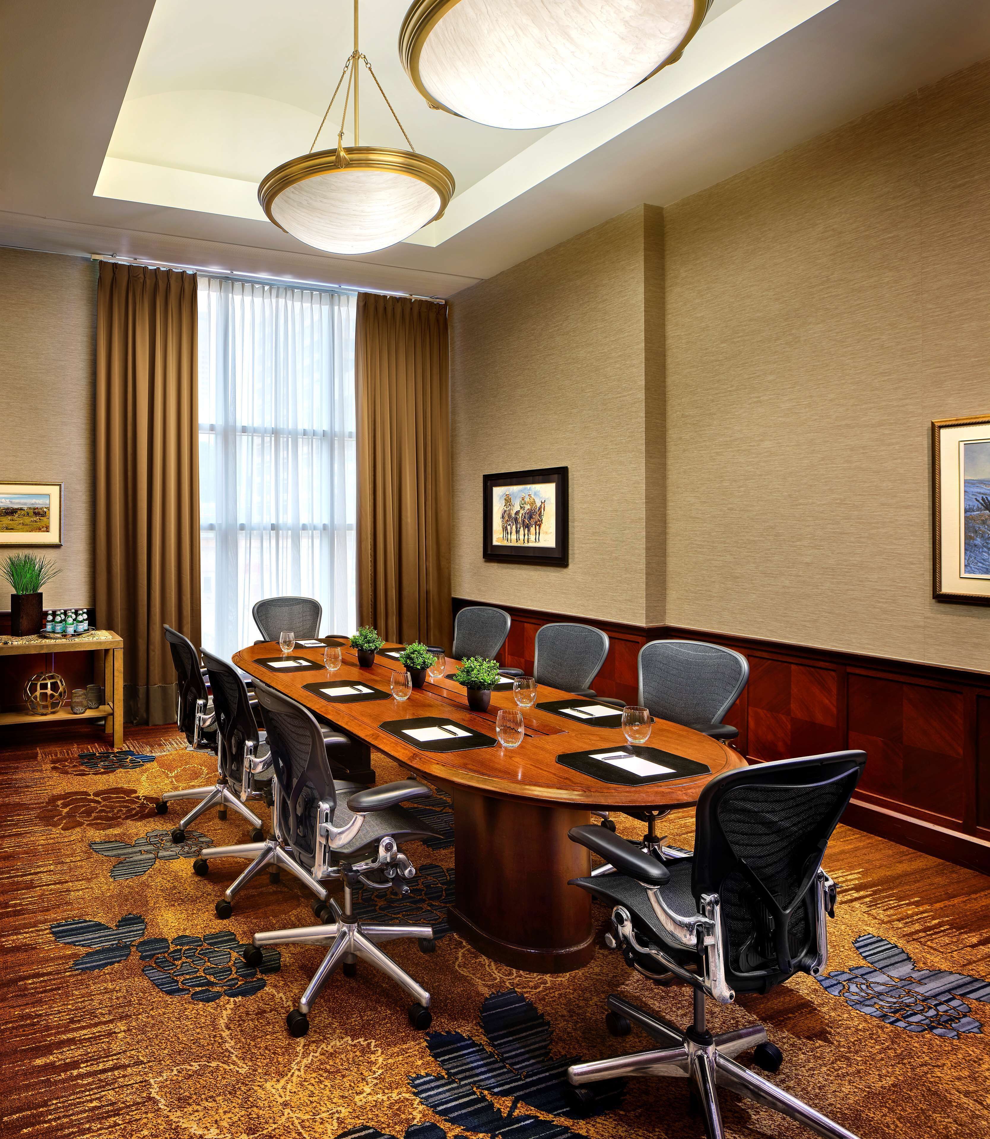 A conference room with a large wooden table, six chairs, and a chandelier.