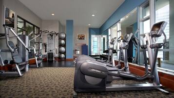 Un gimnasio con máquinas de cardio, pesas y balones de ejercicio.