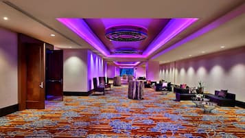 A hotel lobby with a patterned carpet, round tables, and sofas arranged for guests.