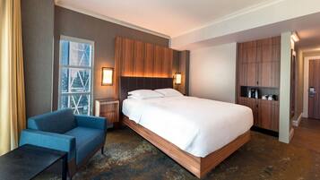 A hotel room with a large bed, a blue sofa, a small table, and a wardrobe.