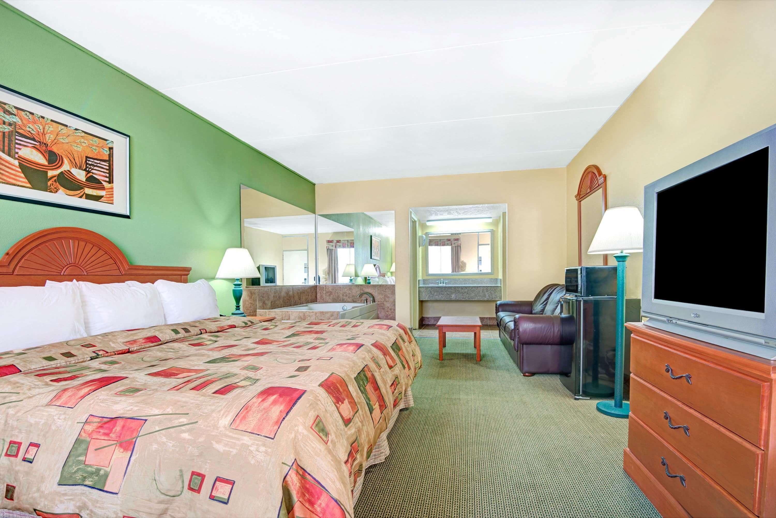 A hotel room with a large bed, a television, a desk, and a chair.