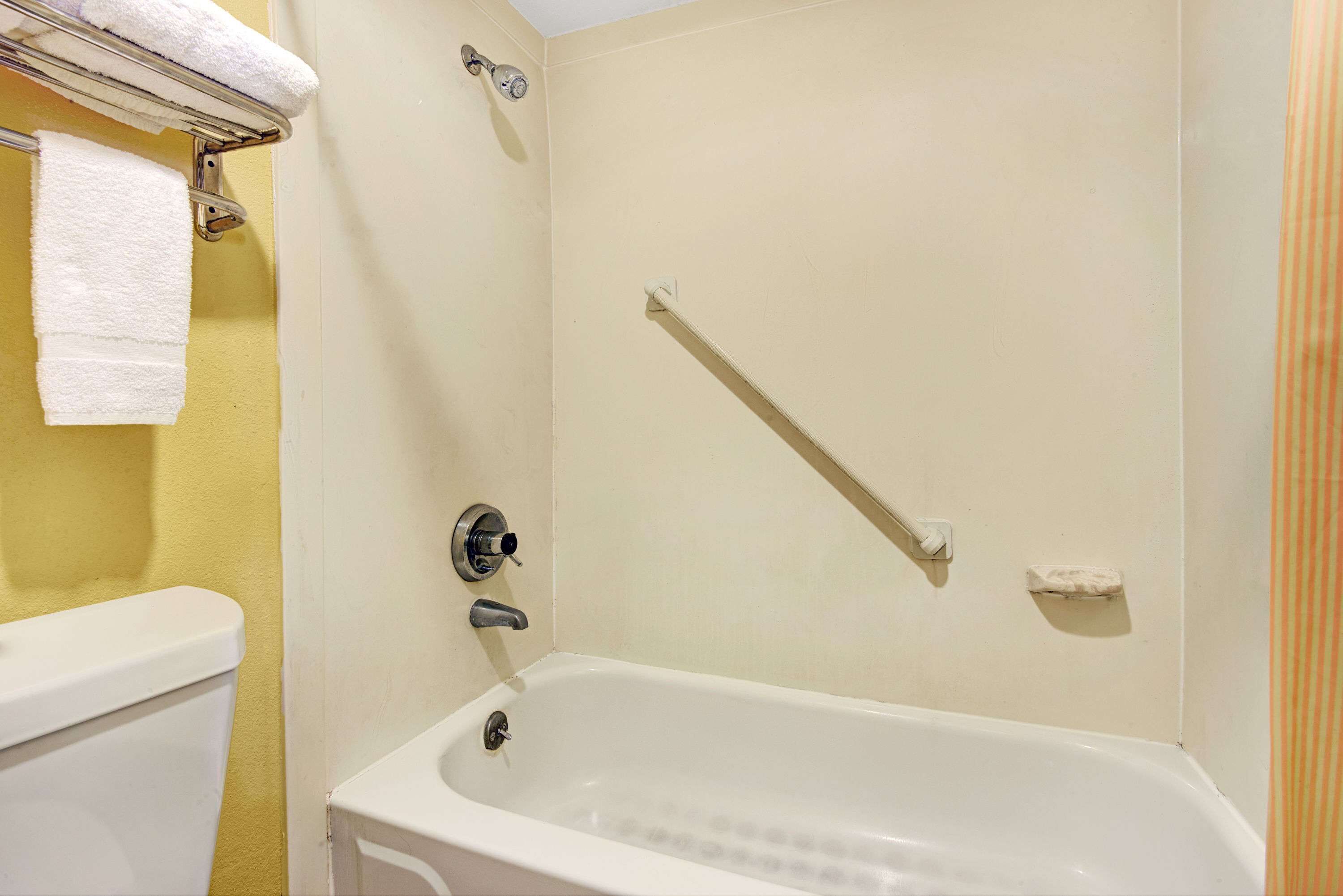 A bathroom with a bathtub, a toilet, and a towel rack.