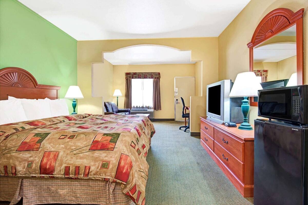 Une chambre d’hôtel équipée d’un lit, d’une télévision, d’un four à micro-ondes, d’un bureau et d’une chaise.