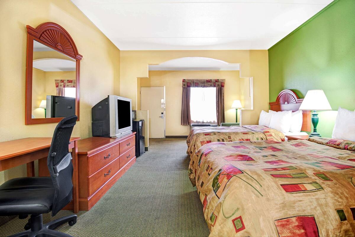 Une chambre d’hôtel équipée d’un lit, d’un bureau, d’une chaise, d’une télévision et d’un miroir.