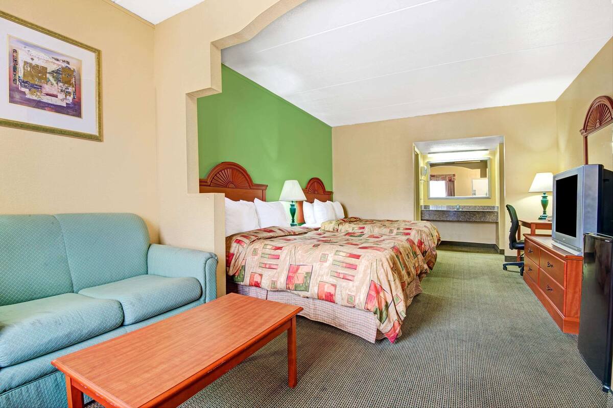Une chambre d’hôtel équipée d’un lit, d’un canapé, d’un bureau, d’une télévision et d’un miroir.