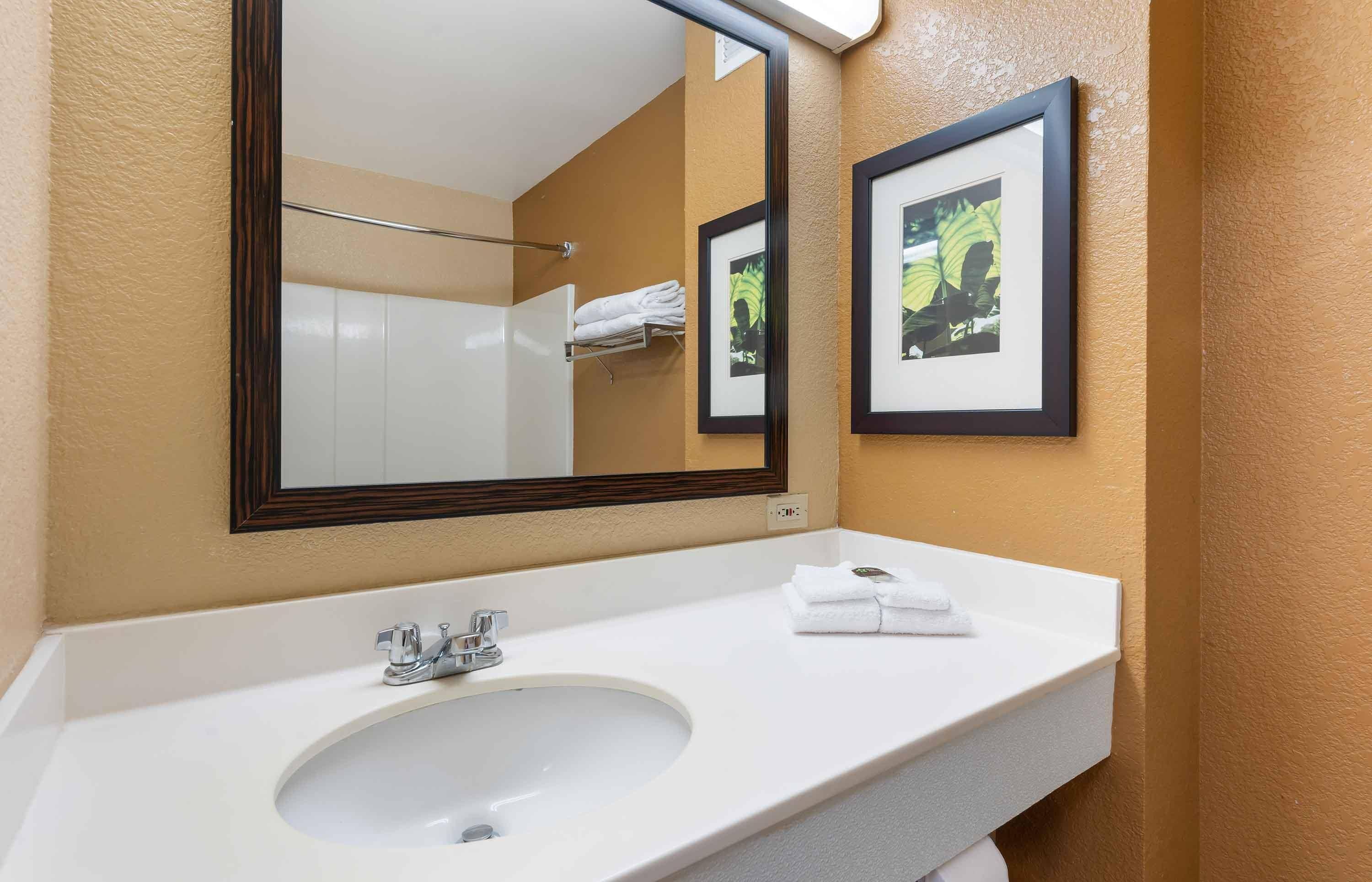 A bathroom with a white sink, a mirror, and two framed pictures on the wall.