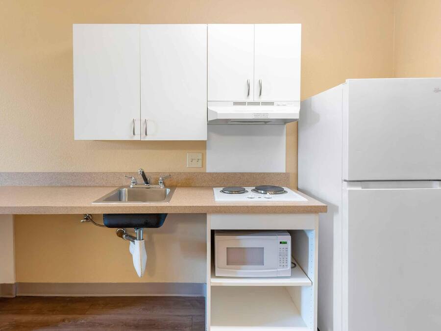 A small kitchen with white cabinets, a sink, a stove, a microwave, and a refrigerator.