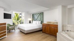 A modern hotel room with a large bed, a wooden cabinet, a bathroom with a bathtub, and a view of palm trees through the window. - Club Wyndham Santa Barbara (Pompano Beach)