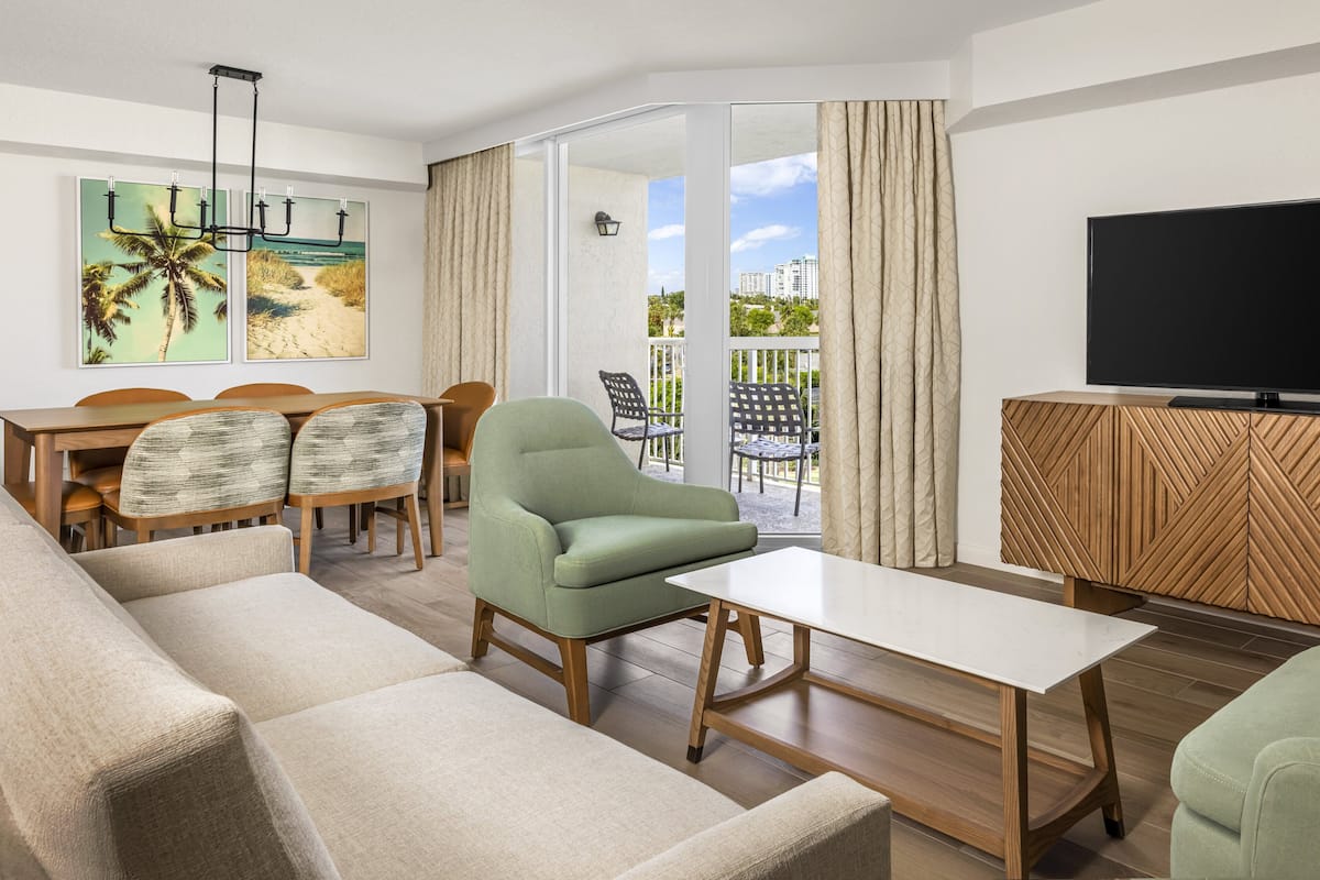 A modern living room with a sofa, armchairs, a dining table, and a TV.