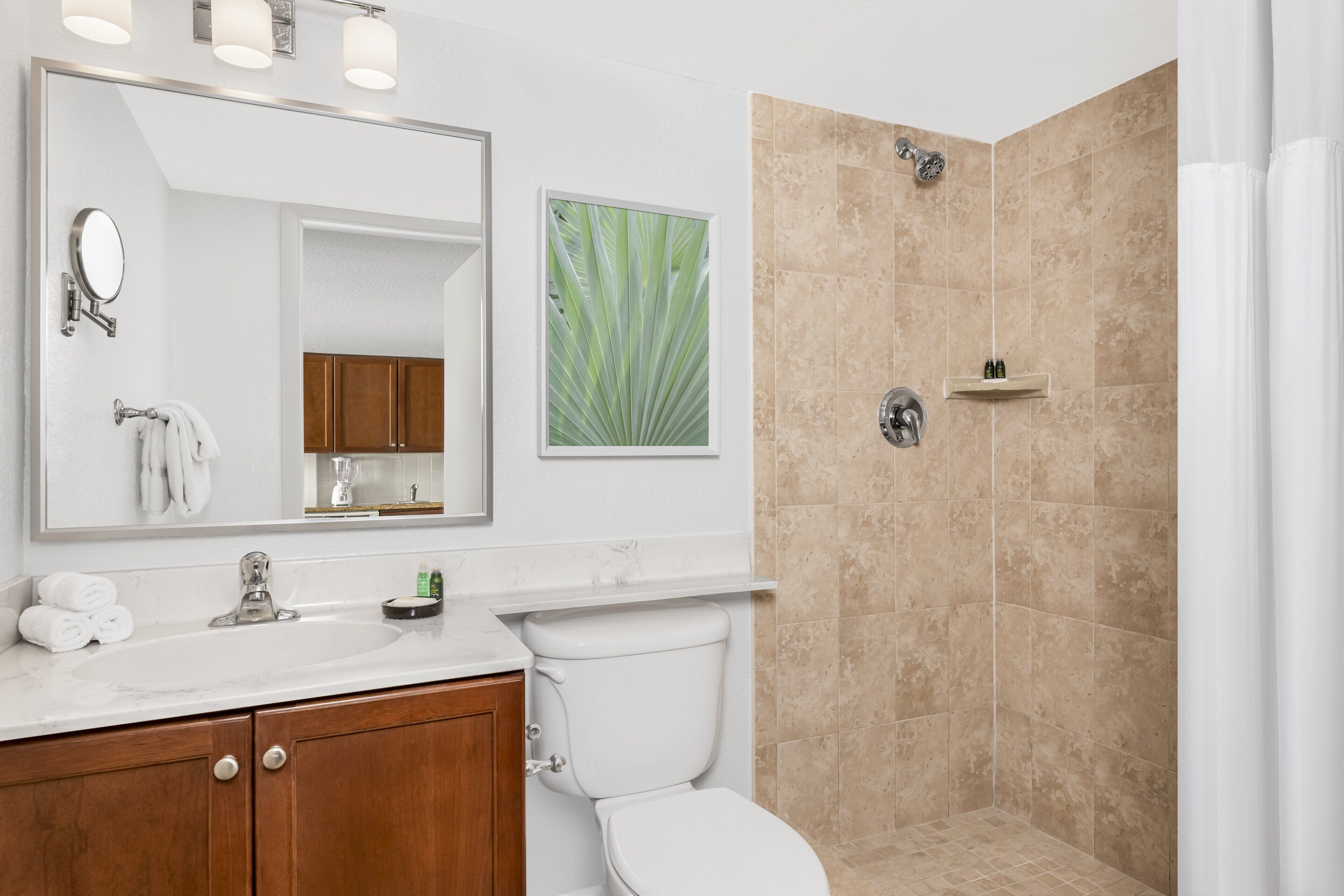 Une salle de bain moderne avec un grand miroir, un lavabo, des toilettes et un espace douche.