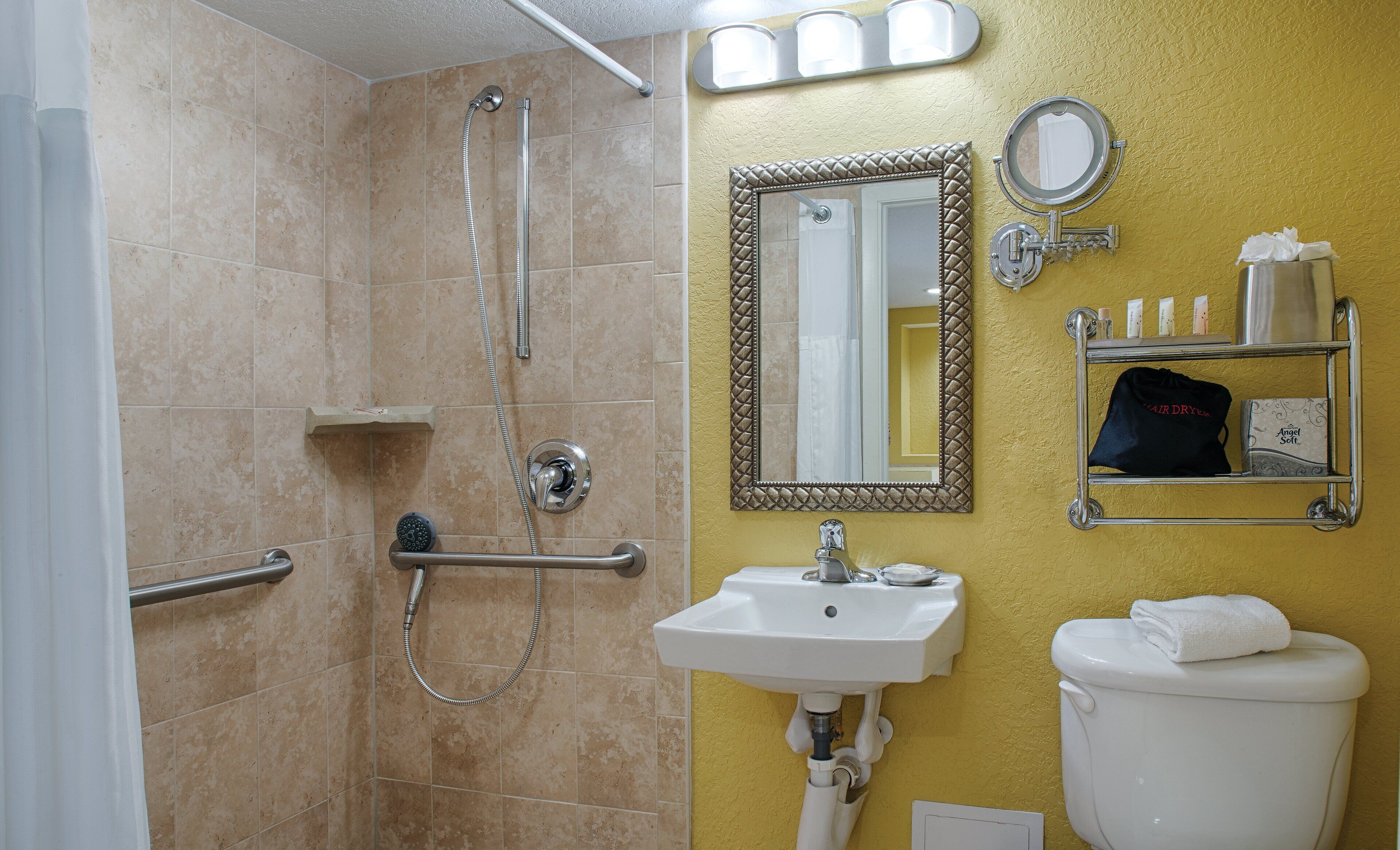 Un baño con ducha, lavamanos, inodoro y espejo con marco decorativo.