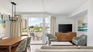 A modern living room with a wooden dining table, two sofas, a TV, and a balcony with a view of high-rise buildings. - Club Wyndham Santa Barbara (Pompano Beach)