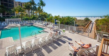 A rooftop pool area with lounge chairs and a view of the beach.