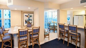 A hotel room with a dining area, a large window with a city view, and a kitchen area. - GullWing Beach Resort (Fort Myers Beach)