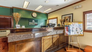 A reception desk with a clock, a framed map, and a sign for HomeTowne Studios. - HomeTowne Studios by Red Roof Atlanta - Chamblee (Chamblee)