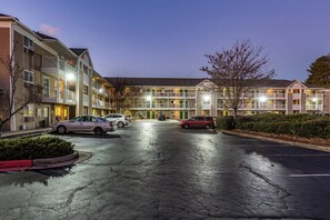A multi-story hotel with a parking lot in front. - HomeTowne Studios by Red Roof Atlanta - Chamblee (Chamblee)