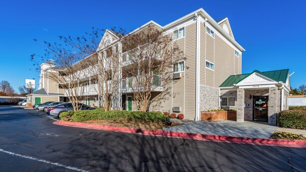 A multi-story hotel with a green roof, parking lot, and a sign for Home Towne Studios.