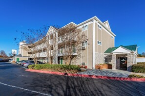 A multi-story hotel with a green roof, parking lot, and a sign for Home Towne Studios.